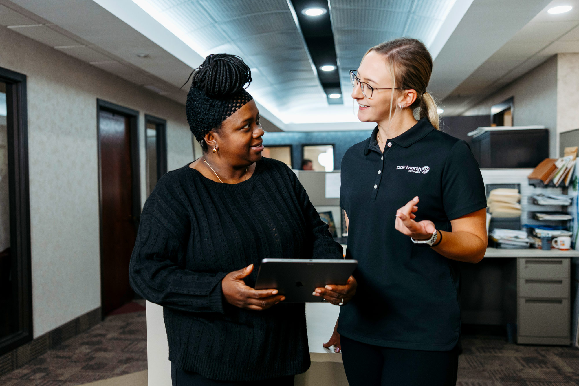 Two women speaking to each other while looking at a tablet