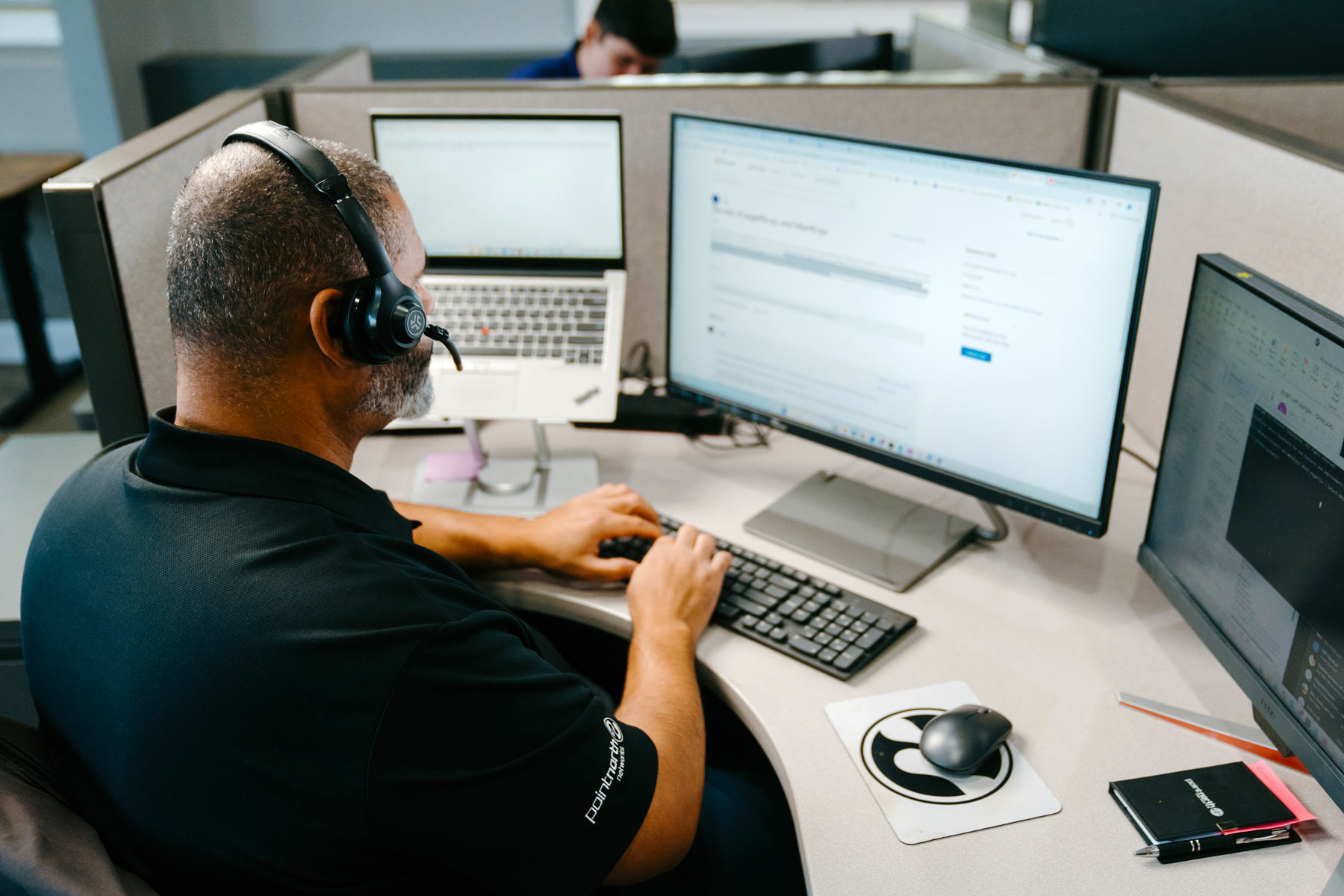 Man working at desk on computer with headphone one