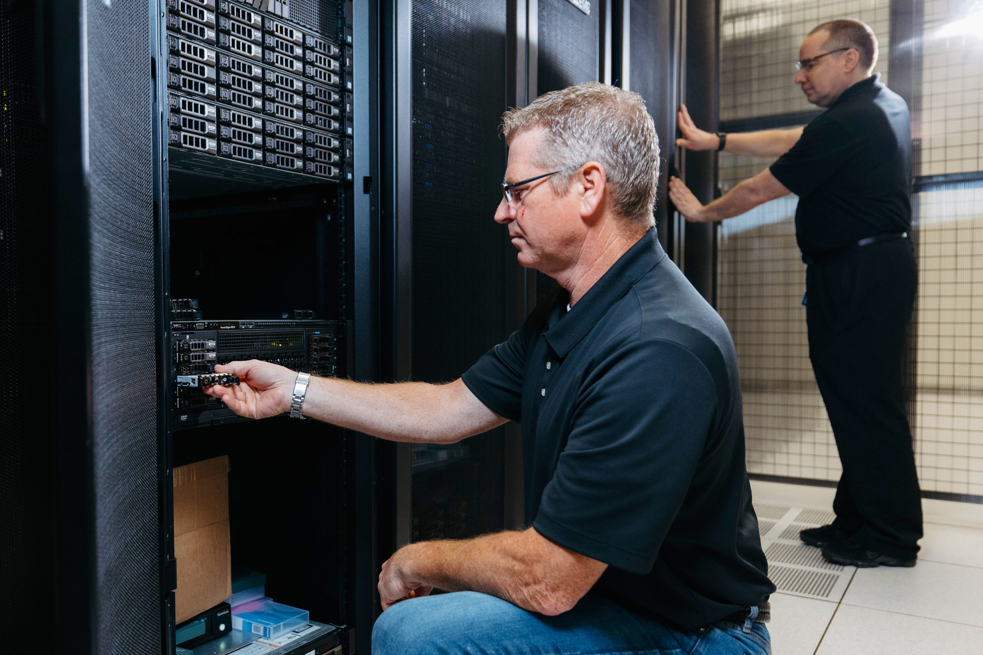 Man bending down to work on a machine at a data center